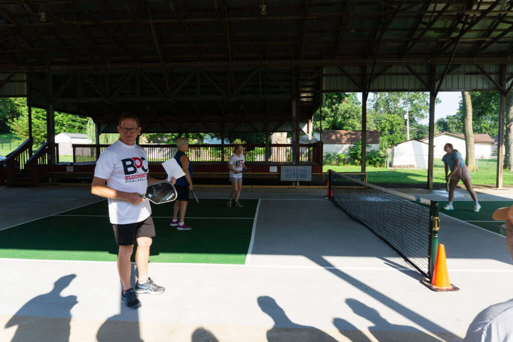 Players participating in a pickleball game under a pavilion at the Ellettsville event.