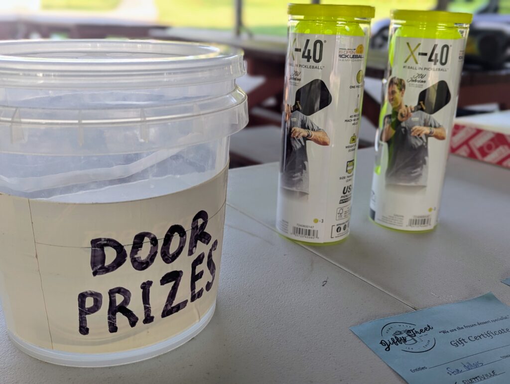 Door prizes including pickleball items displayed on a table at the Ellettsville pickleball event.