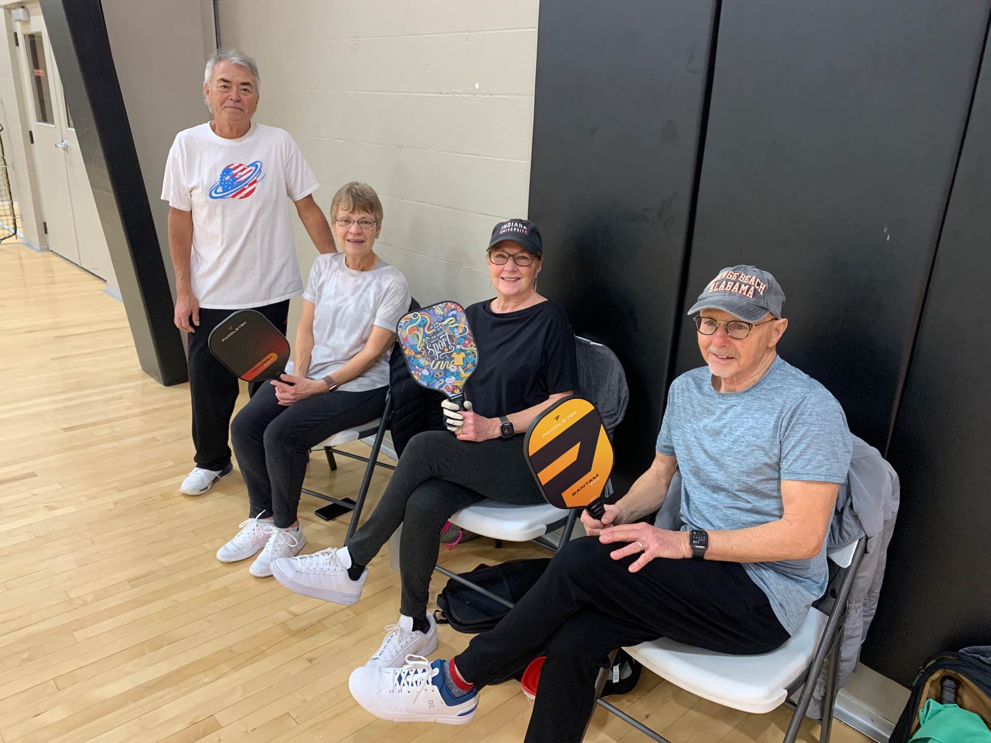 A group of four senior pickleball players at the Southeast YMCA in Bloomington, Indiana, holding their paddles and smiling.